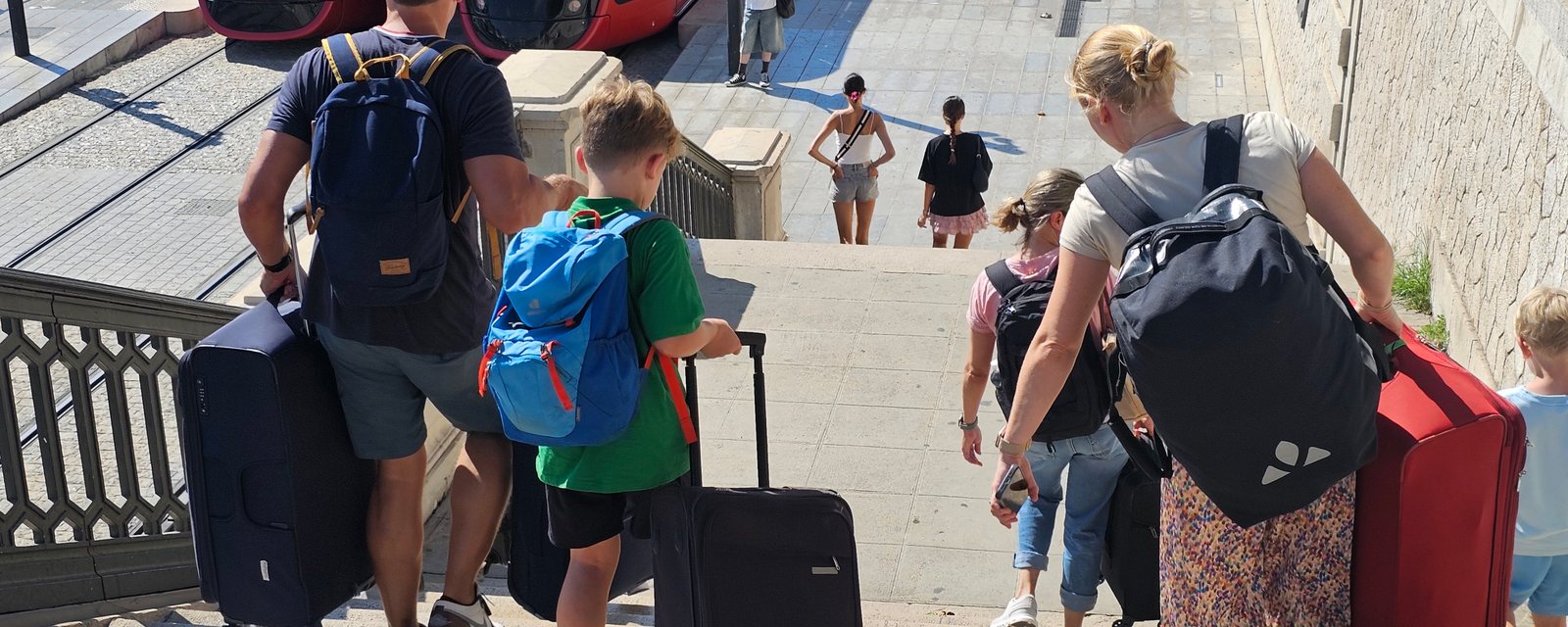 Family with luggage at a tram stop in Nice