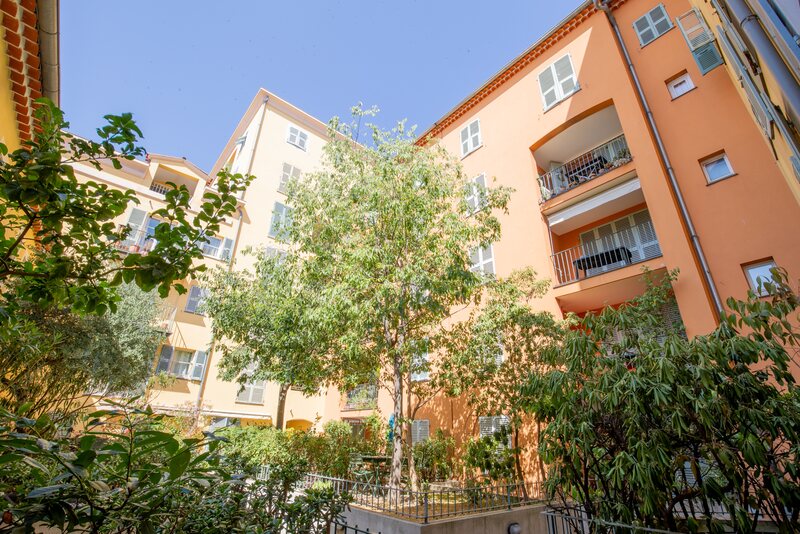 Apartment buildings with pale orange facades, balconies and a planted courtyard